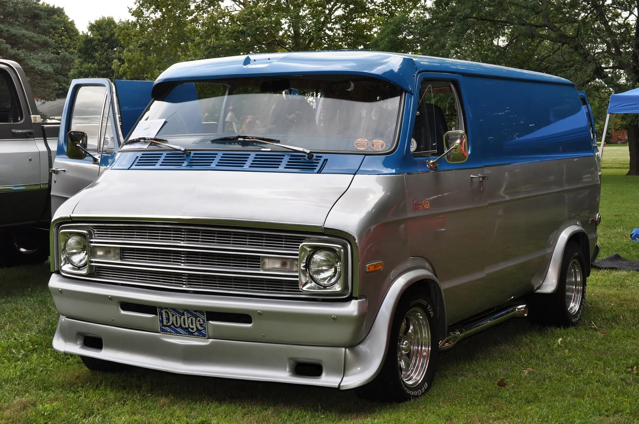 A customized blue and silver Dodge van at the car show