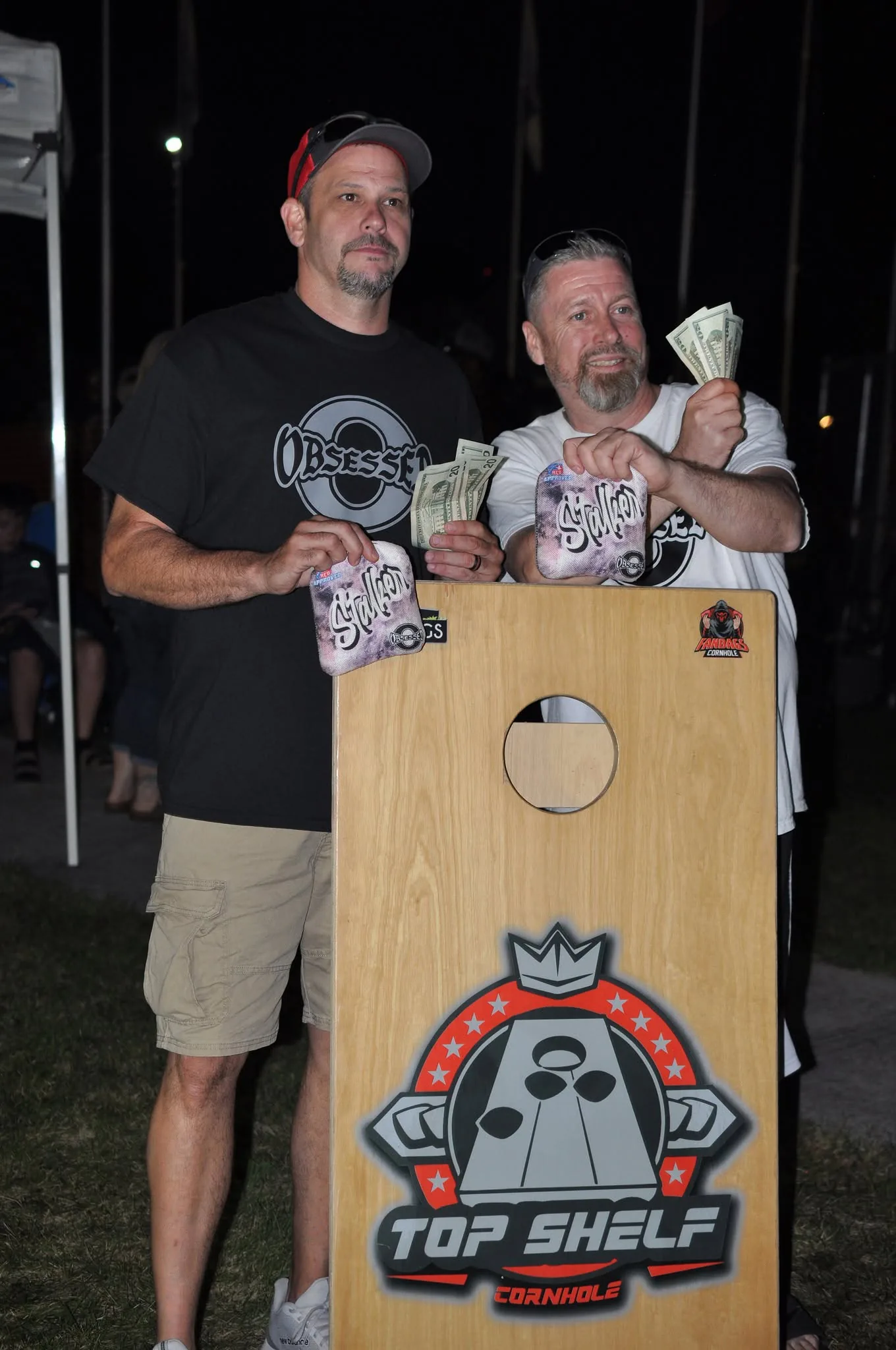 Cornhole tournament winners holding their prize money