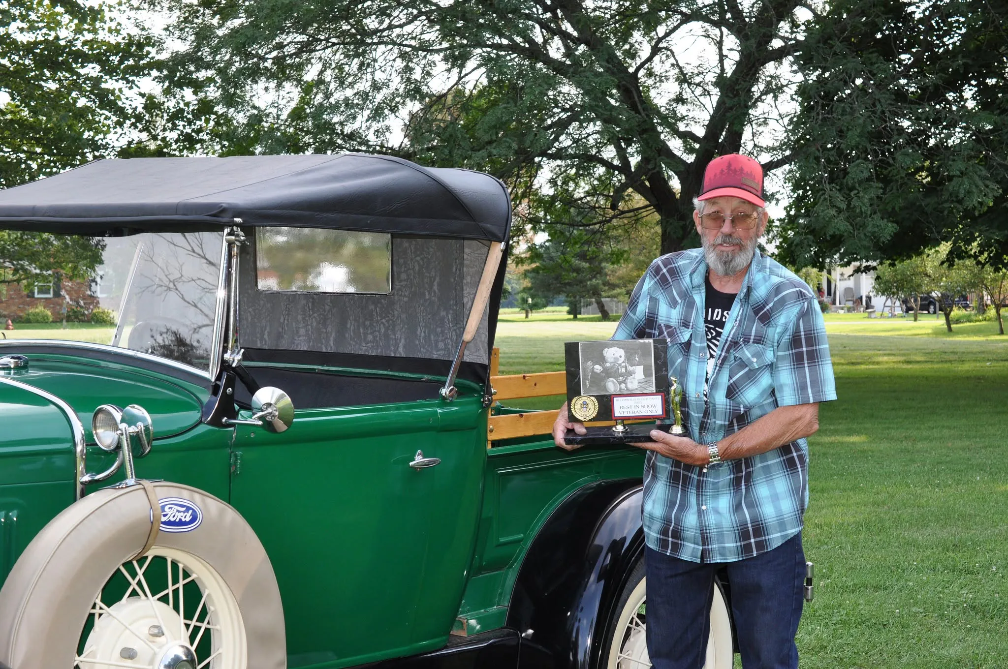 Car show award winner standing beside a restored green Ford